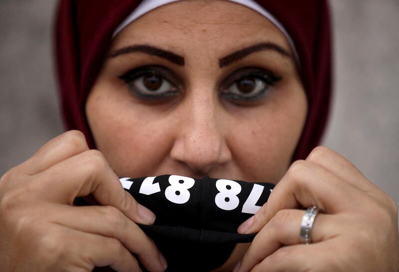 A Lebanese woman displays a protective mask hiding a hot number distributed by the NGO ABAAD in Beirut on 08 December 2020.
ABAAD a resource center for gender equality distributed masks to women and social workers in Beirut, with the 24/7 helpline of the NGO hidden inside the mask. Many women who are on the frontline, providing safety to their families and their surroundings, are still at risk of sexual harassment, abuse and gender-based violence. (Photo by PATRICK BAZ / ABAAD)