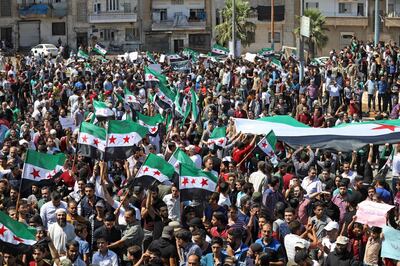 Syrian protesters wave their national flag as they demonstrate against the regime and its ally Russia, in the rebel-held city of Idlib on September 7, 2018. - Damascus has every right to take back all its territory, Russian President Vladimir Putin told a summit on September 7 expected to decide the fate of Syria's last major rebel bastion Idlib. The legitimate Syrian government has a right and must eventually take under control all of its national territory," Putin told Iran's Hassan Rouhani and Turkish leader Recep Tayyip Erdogan at the summit. (Photo by OMAR HAJ KADOUR / AFP)