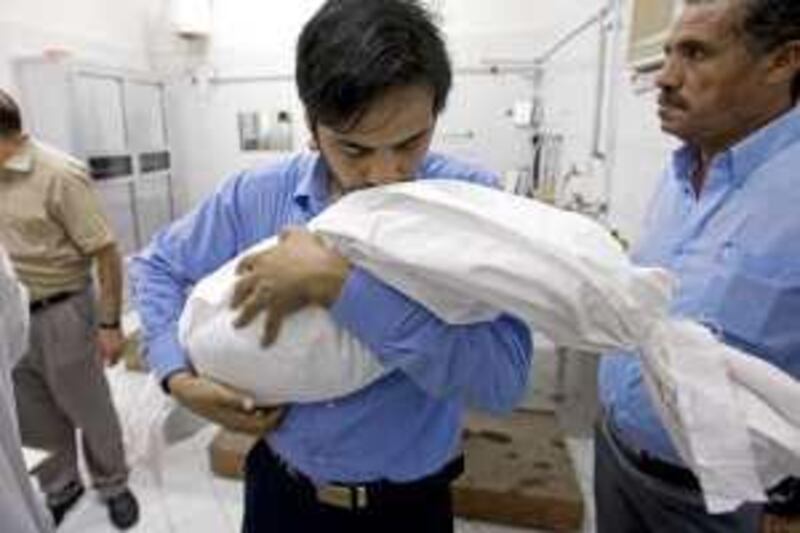 Ajman- March 31, 2010 -Hassan Bakari carries the wrapped body of his son Suhail from the al magasala at Sheikh Zayed Mosque in Ajman where Suhail's and Hassan's other son Ali's bodies were washed and wrapped before their burial in Ajman, March 31, 2010. The five month old boys died after inhaling a pesticide used to fumigate their neighbor's flat March 26, 2010. (Photo by Jeff Topping/The National) 
 