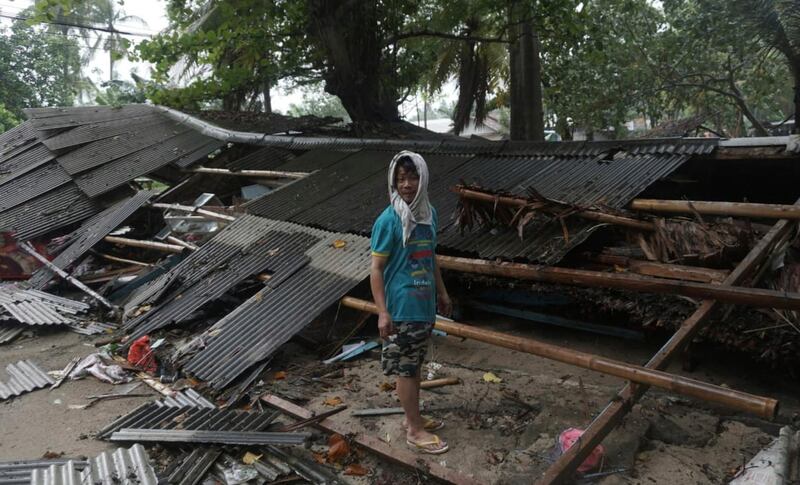 A man inspects his house which was damaged by a tsunami, in Carita, Indonesia. AP