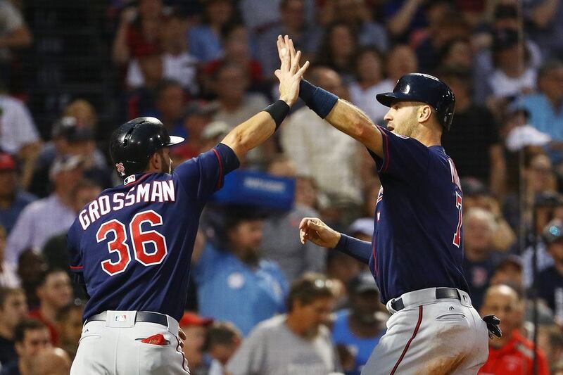 Joe Mauer, right, high fives Robbie Grossman of the Minnesota Twins after scorig in the fourth inning of a game against the Boston Red Sox at Fenway Park