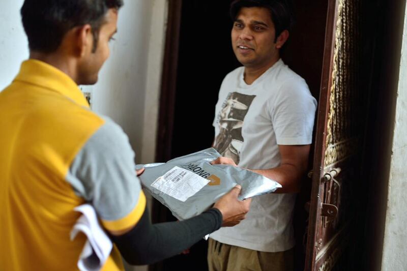 A resident receives a delivery from a Gojavas parcel agency staff, which handles Jabong products in Ghaziabad, India. Pradeep Gaur / Mint via Getty Images