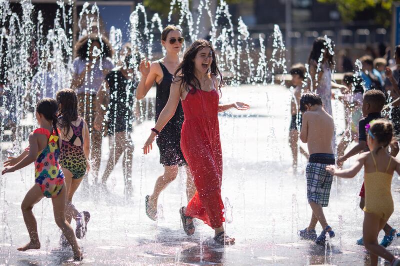 People enjoy the water fountains in King's Cross, London. EPA