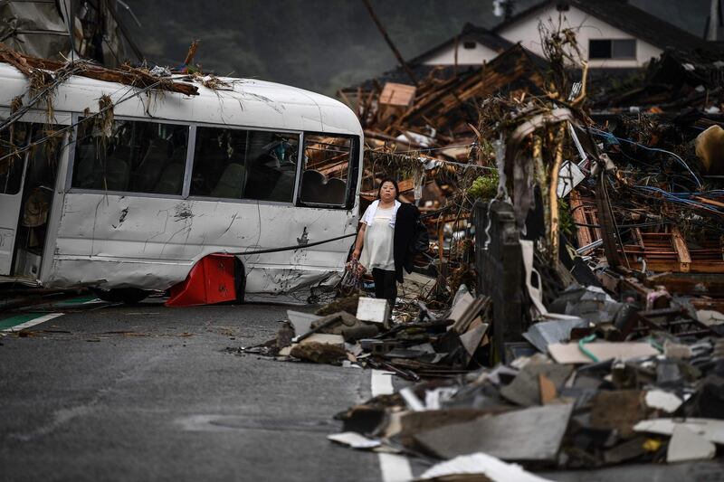 A woman walks amongst debris next to a damaged bus in Hitoyoshi, Kumamoto prefecture in Japan. AFP