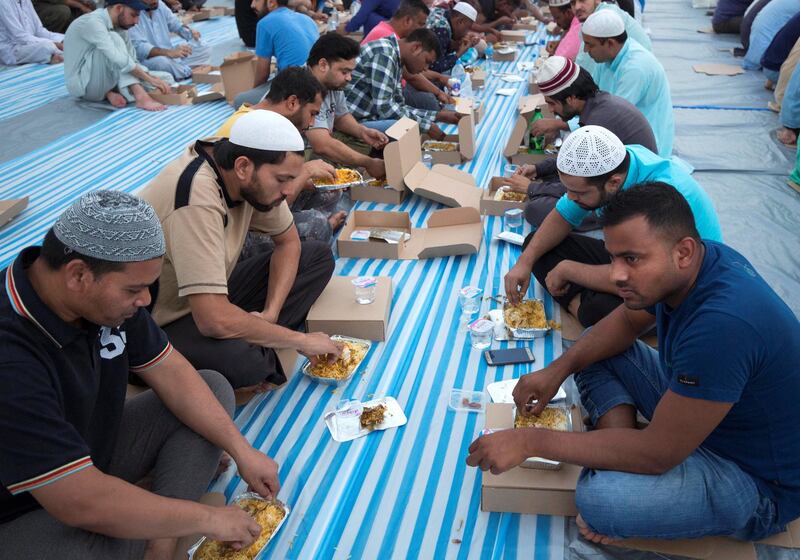 DUBAI, UNITED ARAB EMIRATES -  Workers breaking their fast. Dubai Police join hands with Berkeley Assets to serve up Iftar dinner to mark Laylatul Qadr for 10,000 labourers with seating for 5,000 and another 5,000 laborers will go home with meal boxes in Al Muhaisnah, Dubai.  Ruel Pableo for The National