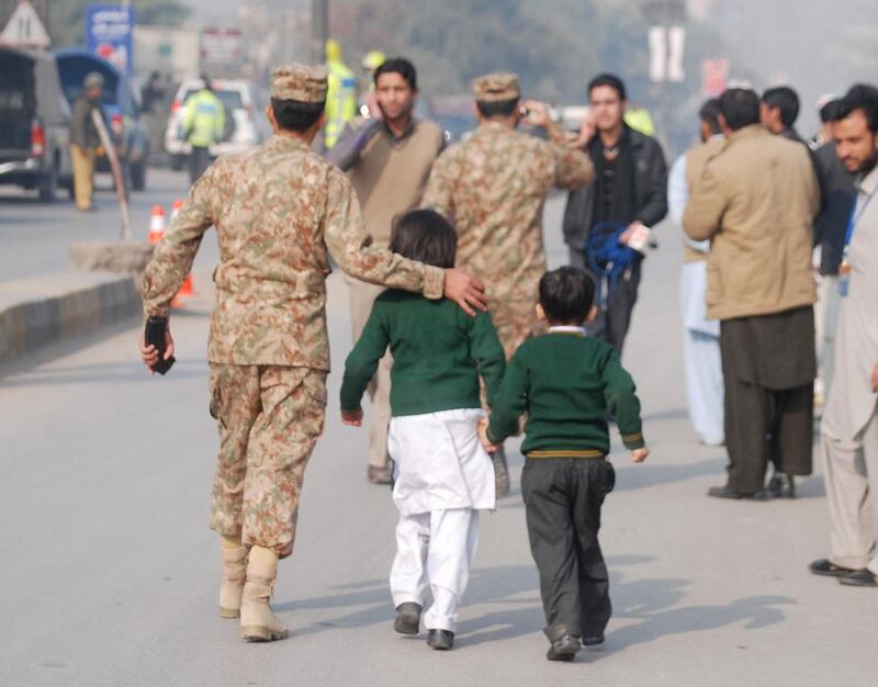 A soldier escorts schoolchildren after they were rescued from the Army Public School that is under attack by Taliban gunmen in Peshawar.  Khuram Parvez / Reuters