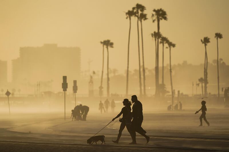 FILE - In this April 18, 2021, file photo, people walk on a beach path as evening winds kick up sand in Long Beach, Calif. California's population has declined for the first time in its history. State officials announced Friday, May 7, that the nation's most populous state lost 182,083 people in 2020. California's population is now just under 39.5 million. (AP Photo/Ashley Landis, File)