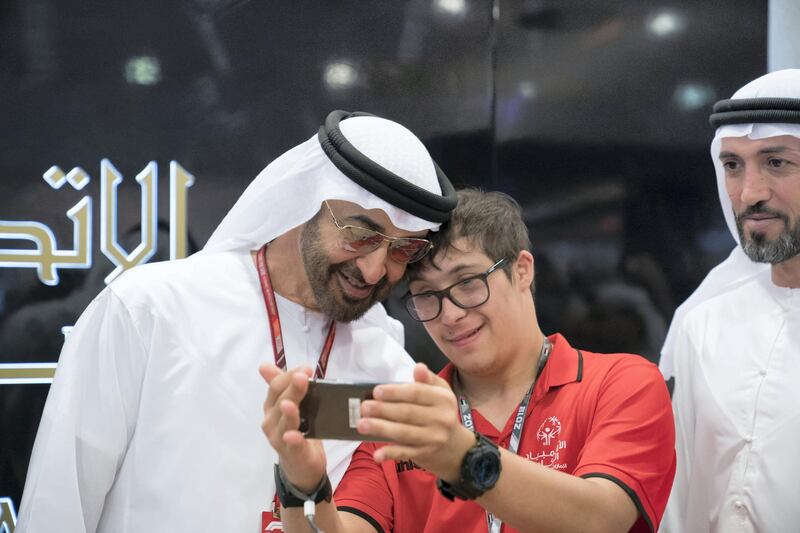 ABU DHABI, UNITED ARAB EMIRATES - November 24, 2018: HH Sheikh Mohamed bin Zayed Al Nahyan, Crown Prince of Abu Dhabi and Deputy Supreme Commander of the UAE Armed Forces (L), stands for a selfe with a participant in the Special Olympics World Games Abu Dhabi 2019, on the second day of the 2018 Formula 1 Etihad Airways Abu Dhabi Grand Prix, at Yas Marina Circuit. Seen with HE Mohamed Mubarak Al Mazrouei, Undersecretary of the Crown Prince Court of Abu Dhabi (R).

( Mohamed Al Hammadi / Ministry of Presidential Affairs )
---