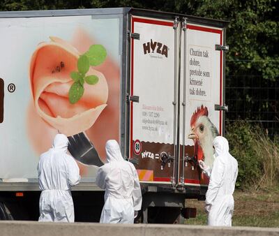 FILE - In this Thursday, Aug. 27, 2015 file photo, investigators stand near an abandoned truck on the shoulder of Highway A4 near Parndorf, Austria, south of Vienna. A Hungarian court has extended the prison sentences of four human traffickers convicted last year for their roles in a 2015 in which 71 migrants suffocated to death in the back of a refrigerated truck found on a highway in Austria. (AP Photo/Ronald Zak, file)