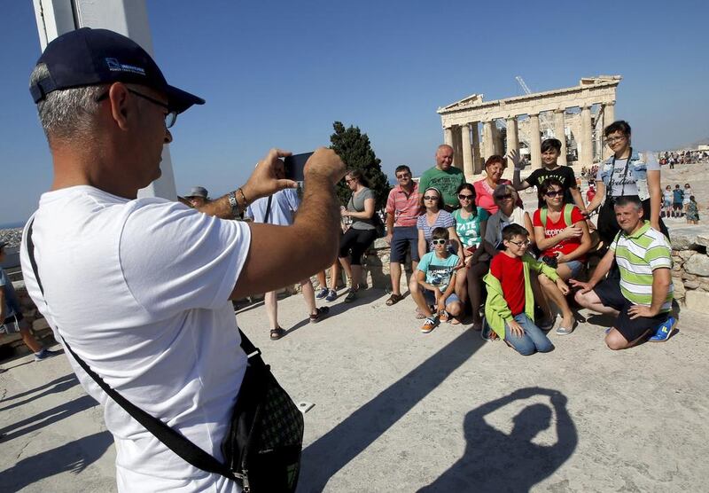 A group of tourists pose for a picture in front of the temple of the Parthenon atop the Acropolis in Athens, Greece, in July 2015. The country said this week it will raise the monthly limit of cash that can be withdrawn from bank accounts as part of measures to ease capital controls imposed three years ago. Reuters