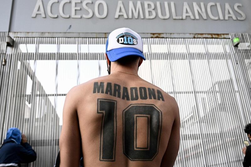 A supporter of Argentine former football star and coach of Gimnasia y Esgrima La Plata Diego Maradona displays his tattoo, outside the hospital where Maradona will undergo brain surgery for a blood clot, in Olivos, Buenos Aires province. AFP