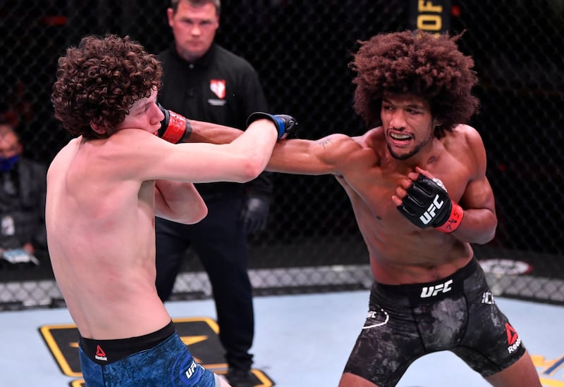 Alex Caceres punches Chase Hooper in their featherweight bout during UFC 250. Reuters