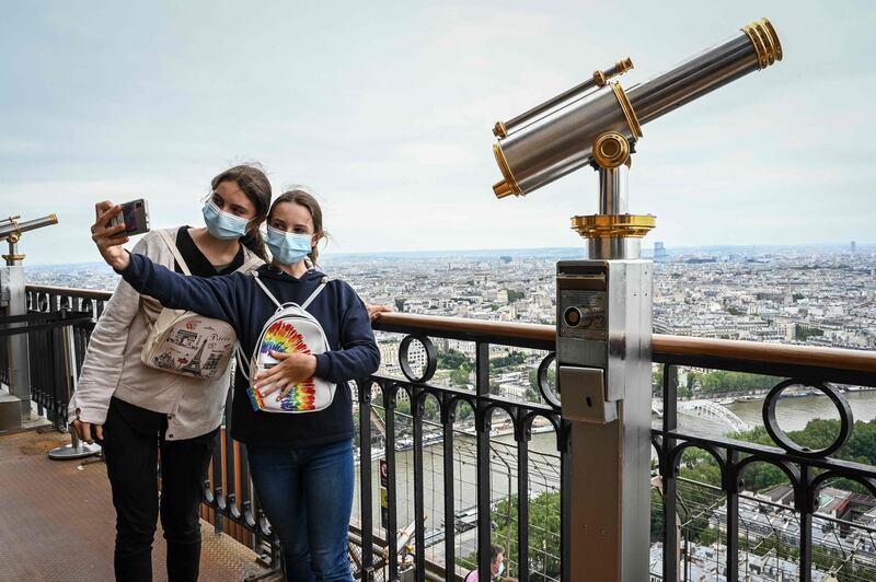 Visitors take a selfie as they visit the Eiffel Tower. The landmark reopened to visitors on July 16, nine months after it was forced to close by the pandemic.