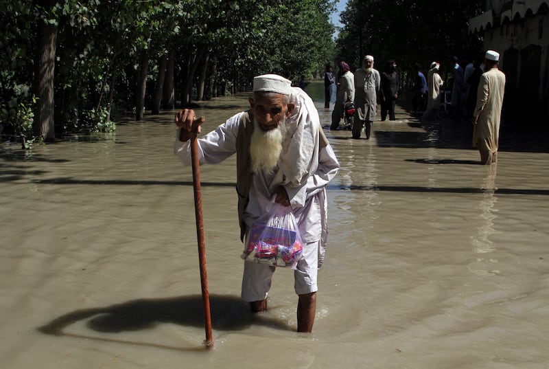 A displaced man wades through a flooded area after fleeing his home on the outskirts of Peshawar, Pakistan. AP