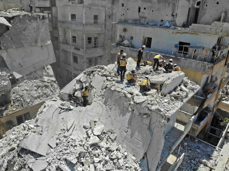 TOPSHOT - Members of the Syrian Civil Defence (White Helmets) search for victims at the site of a reported air strike on the town of Ariha, in the south of Syria's Idlib province on July 27, 2019. Regime airstrikes on July 27 killed 10 civilians in northwest Syria, where ramped up attacks by Damascus and its ally Russia have claimed the lives of hundreds since late April. Idlib and parts of the neighbouring provinces of Aleppo, Hama and Latakia are under the control of Hayat Tahrir al-Sham, a jihadist group led by Syria's former Al-Qaeda affiliate. 
 / AFP / Omar HAJ KADOUR
