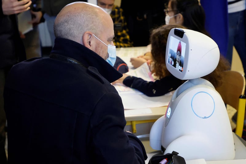 Education minister Jean-Michel Blanquer speaks with a schoolgirl at home, connected with a "Buddy" tele-education robot during a visit at Jules Ferry elementary school on December 3, 2021 in Ormesson-sur-Marne, near Paris.  AFP