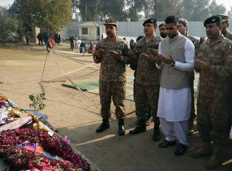 Amir Khan prays with Pakistani military officials at the school in Peshawar on Monday. A Majeed / AFP