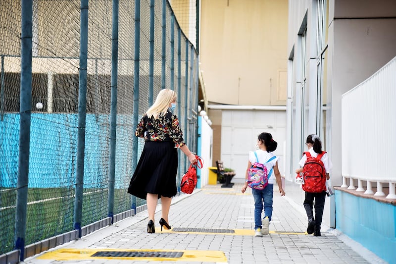 A facility member assists students to their classrooms at the Al-Mizhar American Academy after the government re-opens schools in the wake of the Covid-19 pandemic, in Dubai, UAE, Sunday, Aug. 30, 2020. (Photos by Shruti Jain - The National)