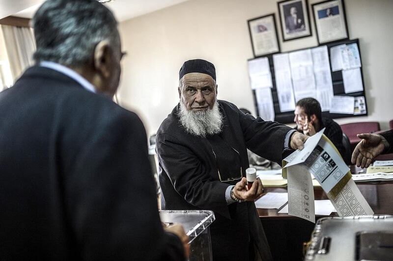 A Turkish man shows another man how to cast his vote in Istanbul on March 23, 2014, ahead of nationwide elections for mayors and local assemblies. Bulent Kilic / AFP 