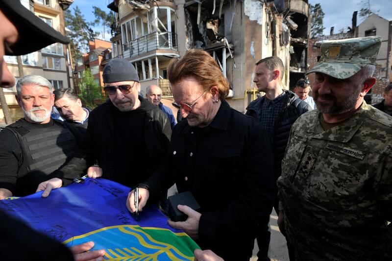 Bono and U2 guitarist the Edge sign a flag during their visit to Irpin. AFP