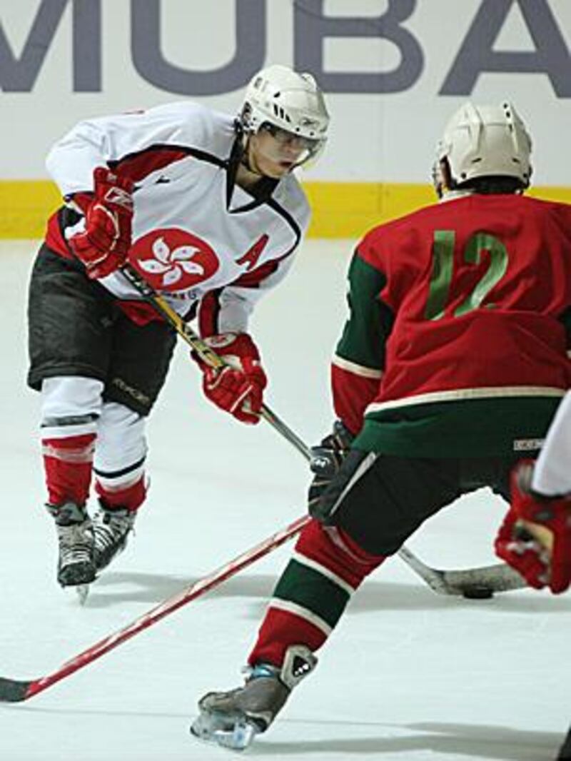 Terence Chim of Hong Kong, left, shoots the puck during his side's 11-0 win over Macau at Zayed Sports City.