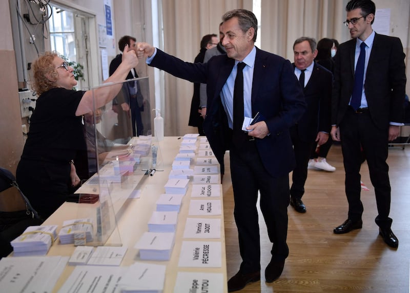 Former French president Nicolas Sarkozy, centre, greets an electoral officer at a polling station in Paris. AFP