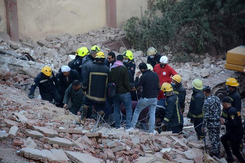 Civilians, and security forces look on as rescue workers search for survivors, with the aid of a bulldozer, in the rubble of a building that collapsed in the Egyptian capital Cairo. AFP