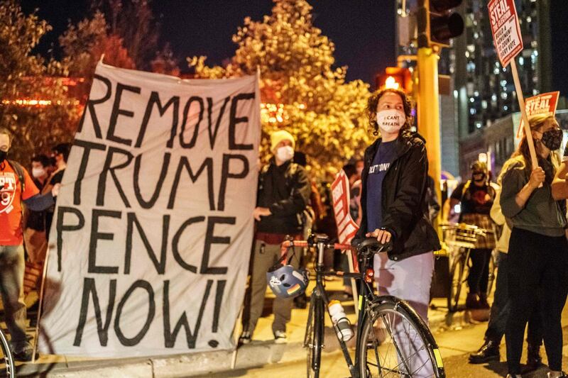 People hold a "Remove Trump Pence Now" sign during a protest against racism and issues with the presidential election after in Minneapolis, Minnesota. AFP