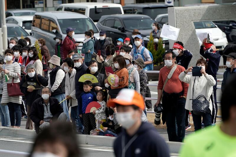 Locals wait for torchbearers at the first section of the Torch Relay in Naraha. AP