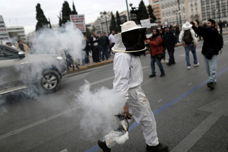 A beekeeper holding a smoker attends a rally of beekeepers in front of the Greek Parliament building in Athens, Greece. EPA 