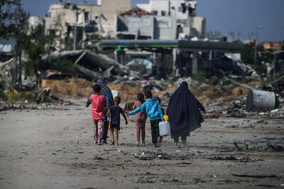 Palestinians walk next to destroyed buildings in Khan Younis, southern Gaza. EPA