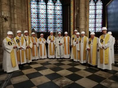 The Archbishop of Paris Michel Aupetit (C) poses with other members of the clergy following the first mass in a side chapel, two months to the day after a devastating fire engulfed the Notre-Dame de Paris cathedral, on June 15, 2019, in Paris. The Notre-Dame cathedral in Paris hosted its first mass on June 15, 2019, exactly two months after the devastating blaze that shocked France and the world. For safety reasons, the mass led by Archbishop of Paris Michel Aupetit was celebrated on a very small scale. Worshippers donned hard hats but priests wore their ceremonial garb. / AFP / POOL / Karine PERRET
