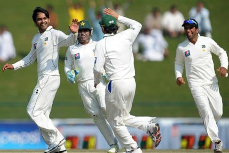 Pakistan's cricketer Mohammad Hafeez (L) celebrates with teammates after dismissing English batsman Alastair Cook (unseen) during the fourth day of the second Test match between Pakistan and England at Sheikh Zayed Stadium in Abu Dhabi on January 28, 2012. AFP PHOTO/LAKRUWAN WANNIARACHCHI

