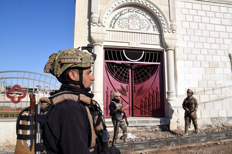 Policemen stand guard as maintenance work is carried out at the Church of the Immaculate Conception in Qaraqosh before the Pope's visit. EPA