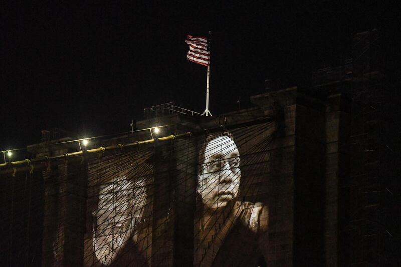 NEW YORK, NY - MARCH 14: Images of New Yorkers lost to the COVID-19 pandemic are projected on to the Brooklyn Bridge on March 14, 2021 in New York City. New York City honors lives lost to COVID-19 on the anniversary of the one year anniversary of the COVID-19 lockdown.   Stephanie Keith/Getty Images/AFP
== FOR NEWSPAPERS, INTERNET, TELCOS & TELEVISION USE ONLY ==
