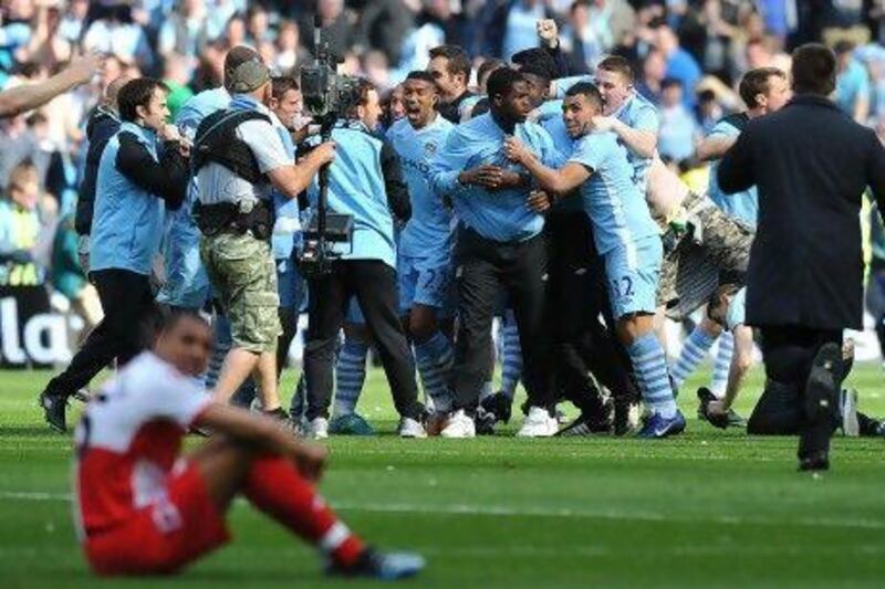 Manchester City's players and supporters celebrate on the pitch after their 3-2 victory over Queens Park Rangers in the English Premier League football match between Manchester City and Queens Park Rangers at The Etihad stadium in Manchester, north-west England on May 13, 2012. Manchester City won the game 3-2 to secure their first title since 1968. This is the first time that the Premier league title has been decided on goal-difference, Manchester City and Manchester United both finishing on 89 points. AFP PHOTO/PAUL ELLIS

RESTRICTED TO EDITORIAL USE. No use with unauthorized audio, video, data, fixture lists, club/league logos or 'live' services. Online in-match use limited to 45 images, no video emulation. No use in betting, games or single club/league/player publications.
 *** Local Caption *** 507753-01-08.jpg