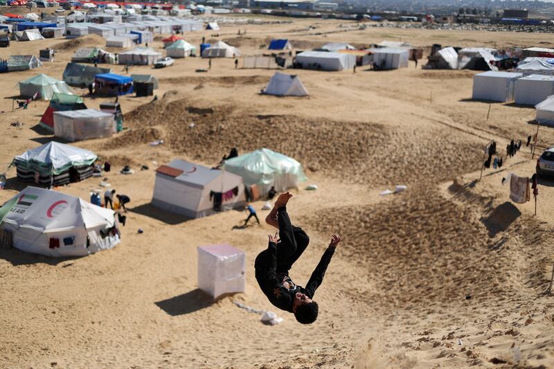 A boy practises his backflip technique in a tent camp for Palestinians displaced by Israeli strikes, near Rafah, southern Gaza. Reuters