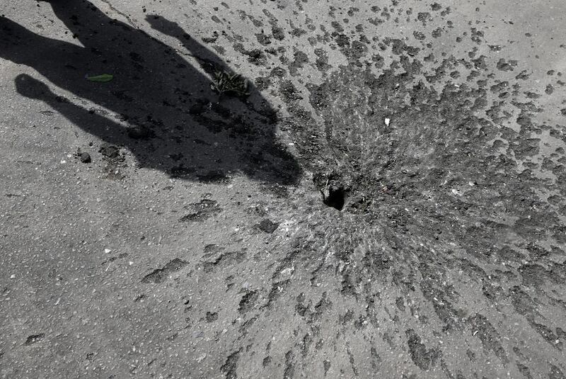 The pockmarked tarmac following a mortar shell explosion on a road near Andriyivka village outside Slaviansk. Russian President Vladimir Putin ordered all troops stationed along the border with Ukraine to withdraw, the Kremlin said. Maxim Shipenkov / EPA