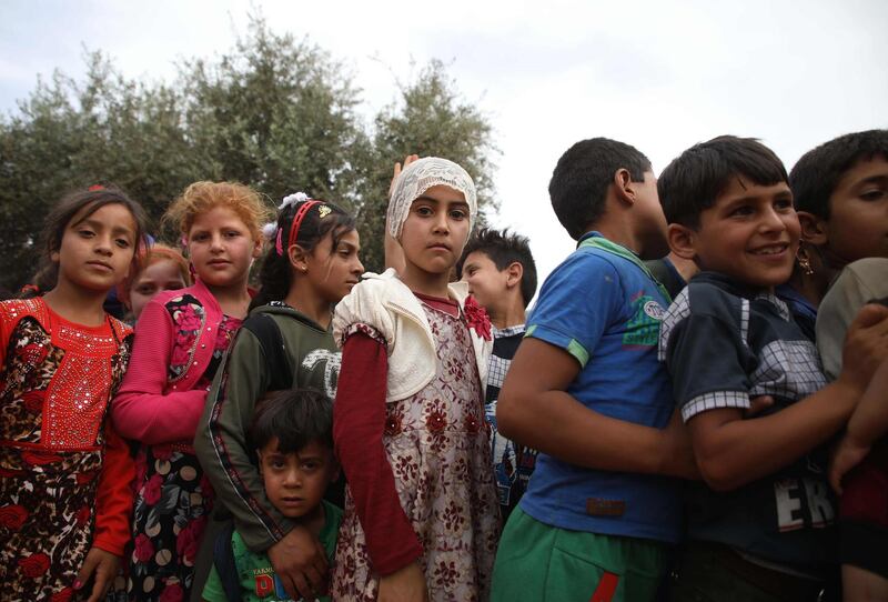 Syrian children queue up while waiting for "The Toy Smuggler of Aleppo" to distribute toys at a DIP camp for Interally Displaced Persons near the town of Aqrabat in Syria's northern Idlib province, on June 4, 2019 as Muslims around the world celebrate Eid al-Fitr, the end of the holy fasting month of Ramadan. The Syrian man who lives in Finland and traveled before Eid used one of the smugglers routes to cross from Turkey into Syria on a mission to cheer up children from his country of origin who were displaced by the war and live in desolate conditions in DIP camps. / AFP / Aaref WATAD
