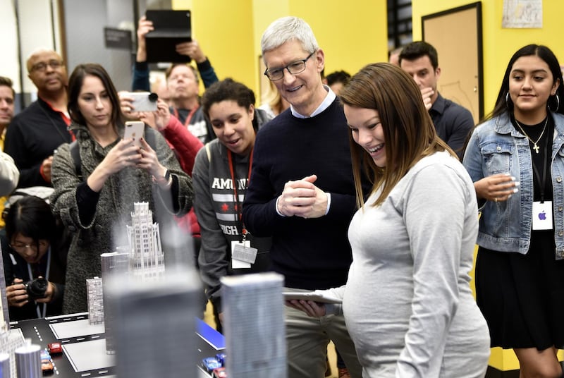 Tim Cook, chief executive of Apple, centre, views a display while touring a technology lab during an event at Lane Technical College Prep High School in Chicago, Illinois. Christopher Dilts / Bloomberg