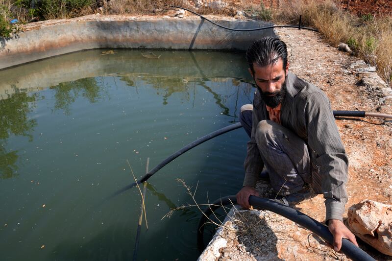 Nazih Sabra sets a tube to pump water from an artificial pond. AP