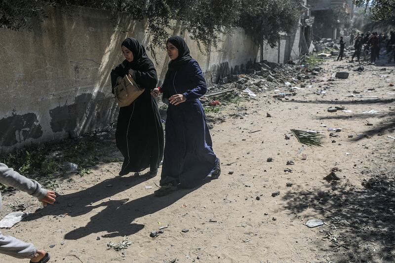 Palestinian women leave Al Nuseirat refugee camp shortly after an Israeli air strike. EPA