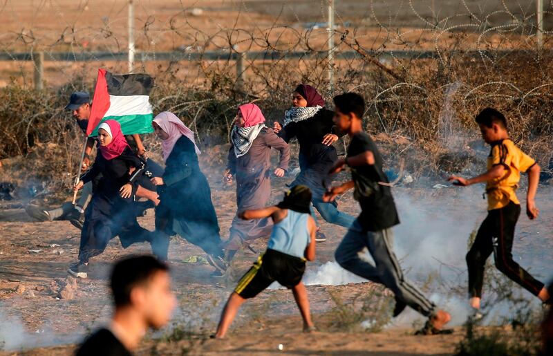 Palestinian protesters run from tear gas canisters fired by Israeli forces amid clashes during a demonstration along the border with Israel east of Bureij in the central Gaza Strip on November 1,  2019.  / AFP / MAHMUD HAMS
