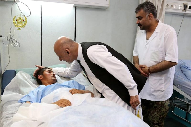 Afghanistan's President Ashraf Ghani talks with a victim wounded in April 21's attack on an army headquarters during his visit in Mazar-i-Sharif. Presidential Palace /Handout via REUTERS. 