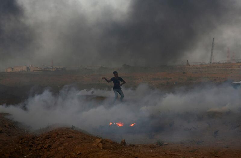 A protester hurls stones while stand in the middle of tear gas fired by Israeli troops near the fence of the Gaza Strip border with Israel, during a protest east of Gaza City. AP Photo