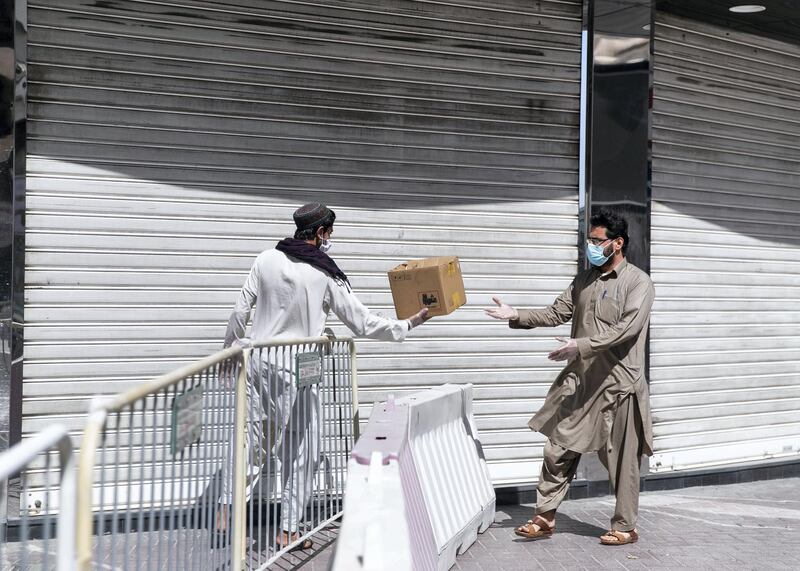 DUBAI, UNITED ARAB EMIRATES. 31 MARCH 2020. 
A man delivers bread across the barricade set at Al Ras neighborhood. 
Dubai’s Supreme Committee of Crisis and Disaster Management announced increased restrictions on movement in Al Ras area of Dubai for two weeks effective from today to facilitate intensified sterilisation procedures. 

@DubaiPoliceHQ
 appeals to the public to cooperate fully with the authorities and abide by all instructions to ensure the preventive measures implemented during the two-week period are a success. People who are not residents of Al Ras are prohibited from travelling to the area.

RTA closed entrances leading to Al Ras area from three main roads and interchanges: Al Musalla, Al Khaleej, and Baniyas Streets. The plan also includes the closure of three stations on the metro green line: Al Ras, Palm Deira and Baniyas Square.

(Photo: Reem Mohammed/The National)

Reporter: NICK WEBSTER
Section: COVID NA 