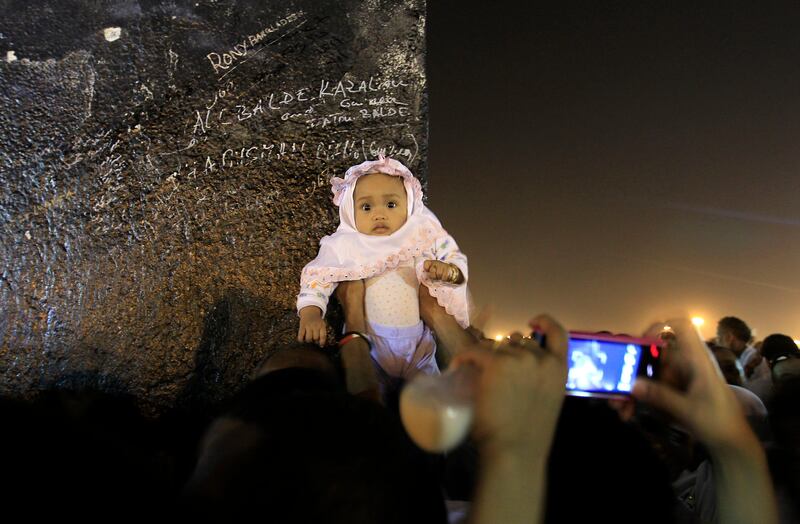 A Muslim pilgrim takes picture for her baby as others pray on a rocky hill called the Mountain of Mercy, on the Plain of Arafat near Mecca, Saudi Arabia, Saturday, Nov. 5, 2011. The annual Islamic pilgrimage draws 2.5 million visitors each year, making it the largest yearly gathering of people in the world. (AP Photo/Hassan Ammar) *** Local Caption ***  Mideast Saudi Arabia Hajj.JPEG-0b772.jpg