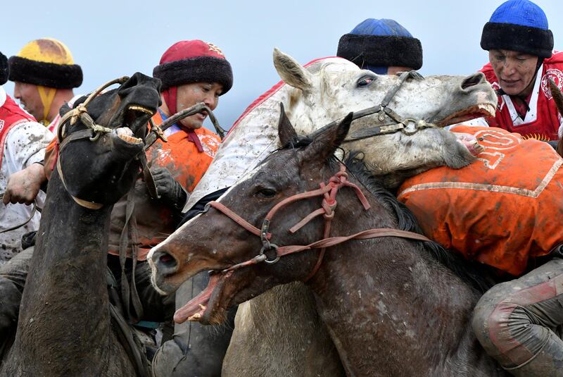 Riders compete during a kok boru, also called ulak tartysh, a traditional game in which players on horseback maneuver with a goat's carcass and score by putting it into the opponents' goal outside Sokuluk village, 20 km (12,5 miles) west of Bishkek, Kyrgyzstan, Tuesday, March 30, 2021. (AP Photo/Vladimir Voronin)