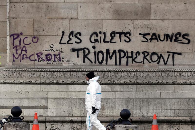 epa07203572 A city employee passes by a graffiti sprayed on the side of the Arc de Triomphe which reads 'the yellow vests will triumph' as police and city employees assess the damages of the 'Yellow Vests' protest a day earlier next to the Champs Elysee in Paris, France, 02 December 2018. The so-called 'gilets jaunes' (yellow vests) are a protest movement, which reportedly has no political affiliation, is protesting across the nation over high fuel prices.  EPA/ETIENNE LAURENT
