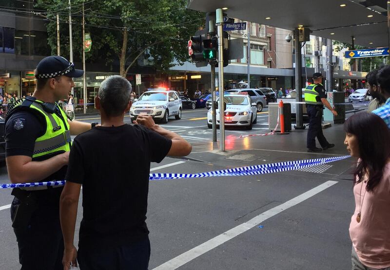 Police officers stand guard as members of the public stand behind police tape after the arrest of the driver of a vehicle that ploughed into pedestrians at a crowded intersection near the Flinders Street train station in central Melbourne on Thursday. Sonali Paul / Reuters